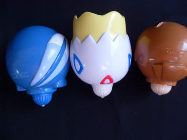 Togepi, Poliwag, and Hoothoot spinning top toys, back view.