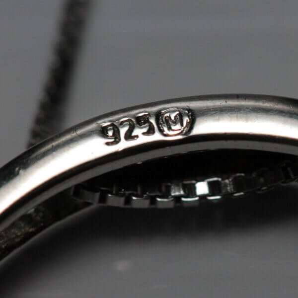 Close up of the maker and purity stamp of a Sterling Silver and Diamond circle pendant.