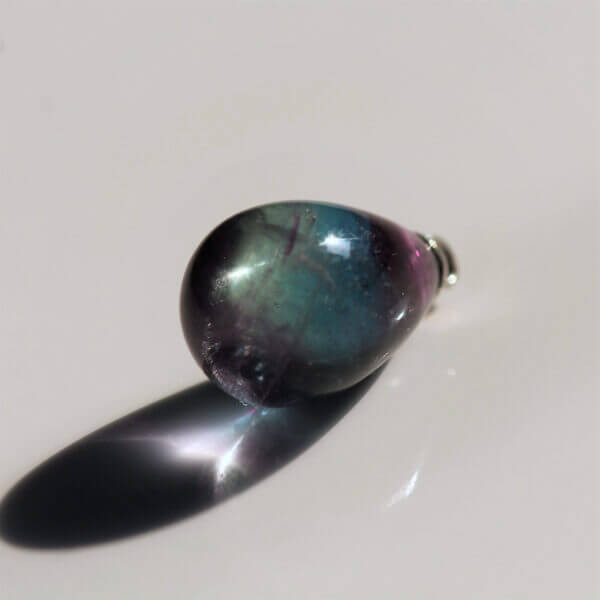 Fluorite, 15x10mm briolette bead, with ring, back view.